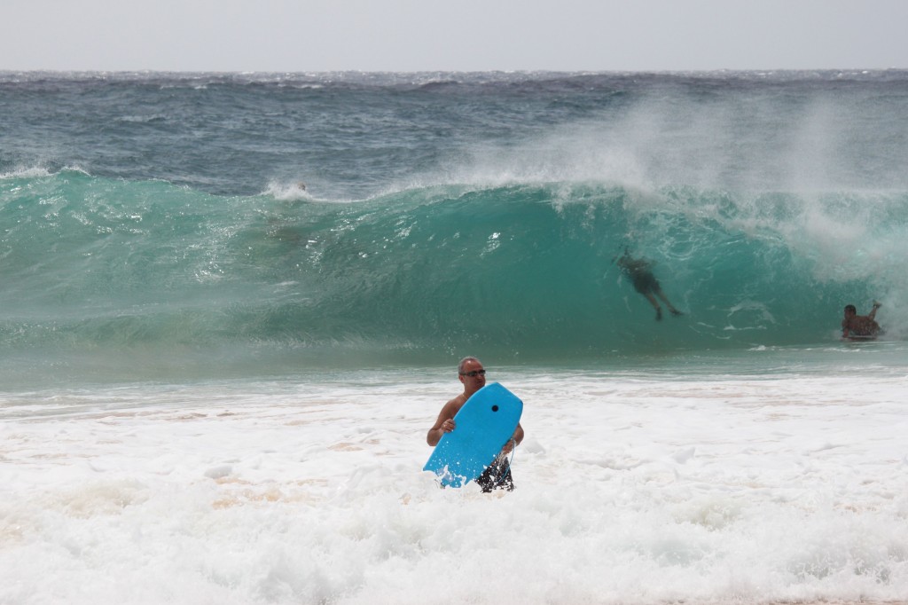 A tourist gets ushered back to shore by lifeguards after trying to get past the shorebreak at Sandy Beach